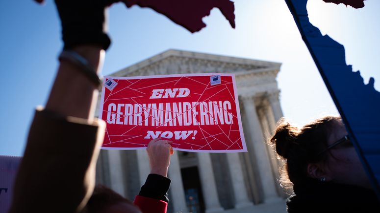 Image of a crowd holding signs outside the Supreme Court; the only one visible reads "END GERRYMANDERING NOW!"